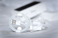 an apple charger and usb cable on a white surface with a laptop in the background