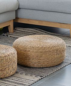 two wicker stools sitting on top of a rug in front of a couch