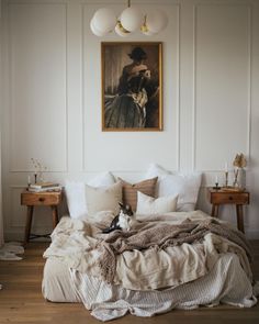 an unmade bed with white sheets and pillows in a bedroom next to a painting on the wall