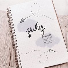 a spiral notebook with the word july written in cursive writing on top of it