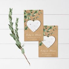 two cards with leaves and hearts on them are sitting next to a vase filled with flowers