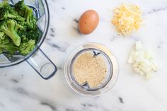 broccoli, eggs and cheese in a blender on a marble counter top