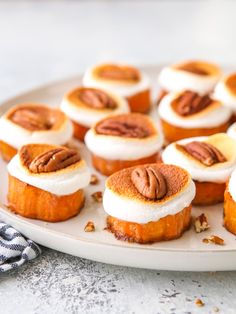 small desserts are arranged on a plate with pecans in the middle and frosting