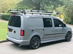 a silver van is parked on the side of the road with its roof rack up