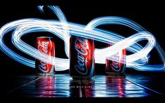 coca - cola cans are lit up with long exposure