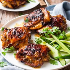 two white plates with chicken, cucumber and green beans on them next to a blue napkin