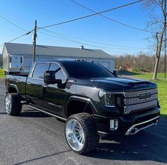 a black truck is parked on the side of the road in front of a house