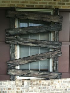 an old window is made out of wooden planks on the side of a brick building