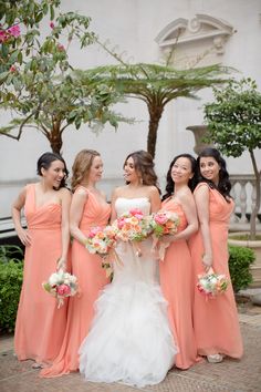 a group of women standing next to each other wearing dresses and holding bouquets in their hands