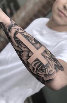 a man with a cross and roses tattoo on his arm