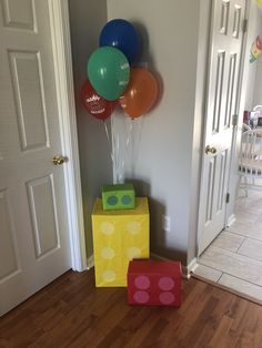 some balloons are hanging on the wall in front of two boxes and one box is sitting on the floor