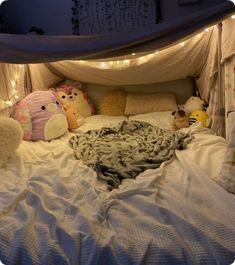 there are stuffed animals on the bed with lights strung above it and in between them is a blanket