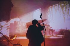 a man standing in front of a microphone on top of a stage with lights behind him