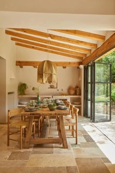 a dining table and chairs in a room with wooden beams on the ceiling above it