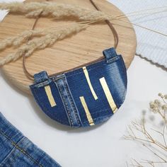 a purse made out of jeans with gold stripes on the front and back pocket, hanging from a wooden hanger