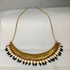 Fire Dance is a large bib bead woven necklace with a golden top bib layered with red, pearl and black seed beads. The red seed beads are intermingled with brown superduo beads. The pearl diamonduo beads and the black flame beads round out the fire dance theme. This bib necklace is large and in charge of the neckline of the wearer. It is also assured to be noticed and appreciated by passersby. Dance Theme, Superduo Beads, Dance Themes, Black Flame, Wonder Woman Logo, Red Pearl, Woven Necklace, Black Seed, Bib Necklaces