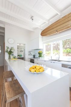 a bowl of fruit sitting on top of a white kitchen counter next to a sink