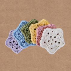 four crocheted coasters sitting on top of a brown paper bag with holes in the middle