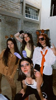 four young women dressed up in costumes posing for a photo with one pointing at the camera