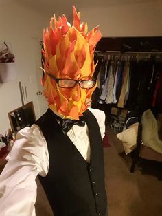 a man in a vest and tie is wearing a paper mask with flames on it