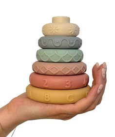 a hand holding a stack of different colored soap bars in front of a white background