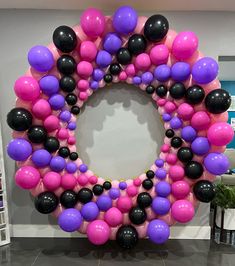 a large balloon wreath with black, pink and purple balloons