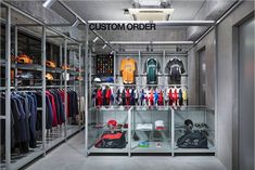 the inside of a clothing store with lots of shirts and hats on display in glass cases