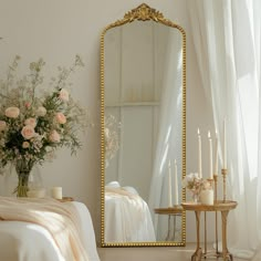 a mirror sitting on top of a table next to a vase filled with flowers