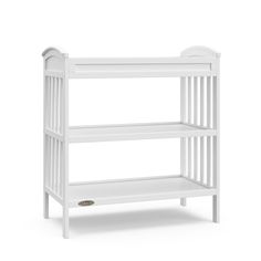 a white baby crib with two shelves on the bottom and one shelf below it