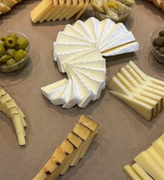 various cheeses and olives are arranged on a table