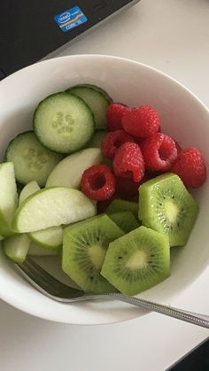 a white bowl filled with cucumber, raspberries and kiwi slices