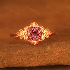 a gold ring with an amethorate stone in the center on top of a rock