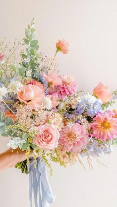 a person holding a bouquet of flowers in their hand with the other hand on it