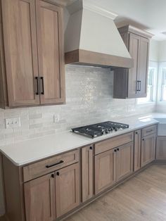 a kitchen with wooden cabinets and white counter tops in front of a stove top oven