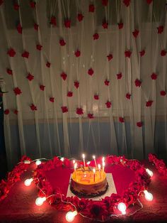 a birthday cake with lit candles sitting on a table