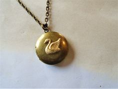 "A round brass locket with a swan on it is hanging from antiqued brass chain. The locket is a darkened brass and the swan is a made of raw brass giving it a golden color. You can select your length of chain at checkout. Locket measures approx. 1\" and opens to hold two small pictures. Necklace will come in a gift box and bow ready for gift giving. Enter back into store: rhondastreasures.etsy.com   RhondasTreasures" Swan Jewelry, Swan Necklace, Mia 3, Dope Jewelry, Small Pictures, Funky Jewelry, Jewelry Lookbook, Jewelry Inspo, Dream Jewelry