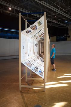 a man standing next to a display in a room filled with wooden floors and walls