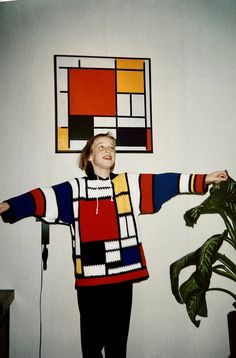 a woman standing in front of a painting on the wall with her arms spread out