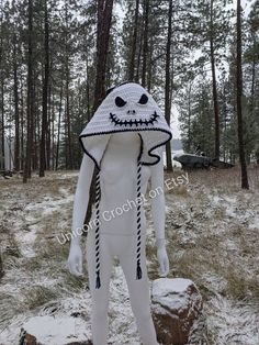 a man in a white costume standing on top of a snow covered ground next to trees