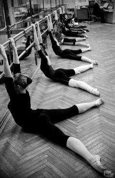 a group of women doing exercises on the floor in front of a row of poles