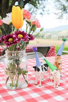 a vase filled with flowers sitting on top of a red and white checkered table cloth