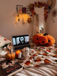 a laptop computer sitting on top of a bed covered in pumpkins and other decorations