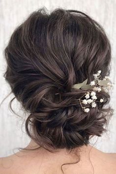 the back of a woman's head with flowers in her hair, wearing a white top