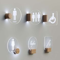 the bathroom signs are on the wall above the toilet paper dispensers and lights