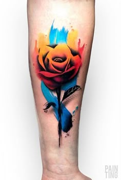 a colorful rose tattoo on the leg with watercolor splashes and ink splatters