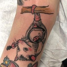 a person with a tattoo on their arm holding a hammer and an animal in the other hand