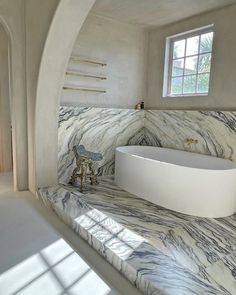 a bathroom with marble counter tops and white bathtub next to window in the corner