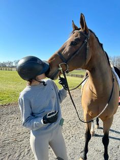 a woman is standing next to a brown horse with a helmet on it's head