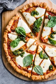 a pizza with cheese, spinach and sauce on a cutting board next to a gray towel