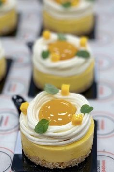 small desserts are arranged on black trays with white and yellow frosted toppings